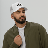 Man wearing the Unshaken Apparel Logo Trucker Hat, representing faith and strength in a casual outfit.