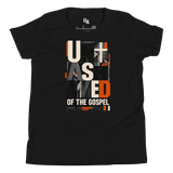 Unashamed Romans 1:16 Youth T-Shirt in black featuring bold typography and orange accents, representing faith in God.
